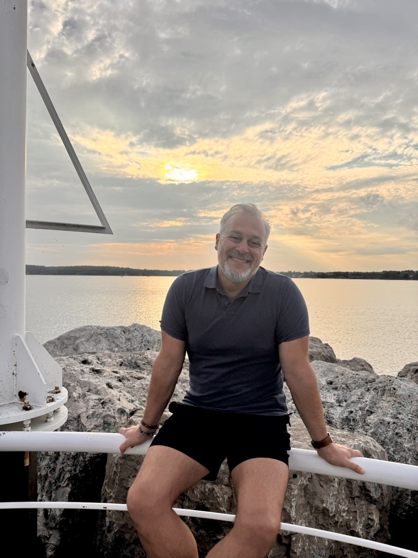 Philip Rosi sitting on the pier railing at golden hour